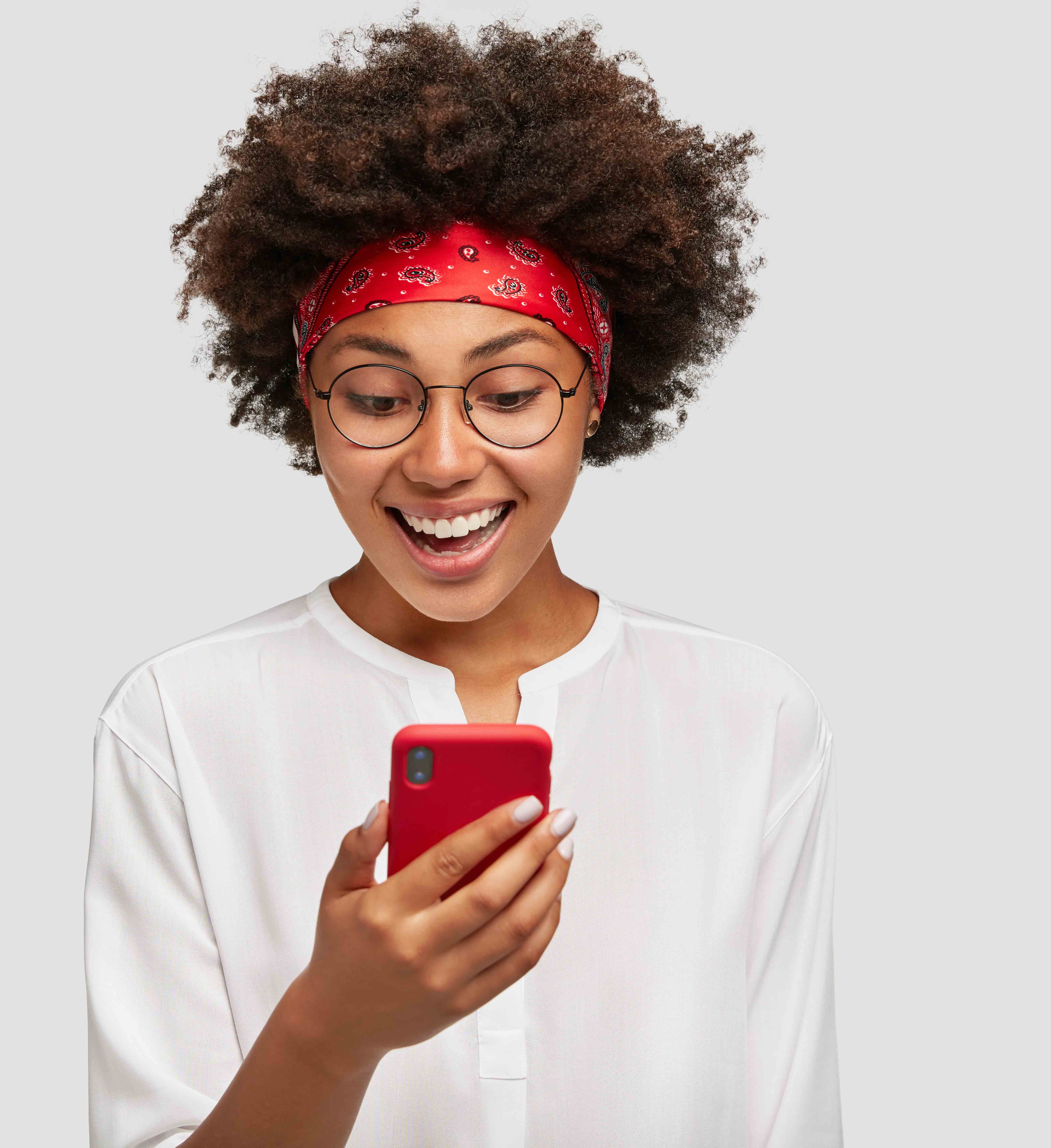 Horizontal shot of pleasant looking black adult, excited with video chat, carries up to date cell phone, has broad smile, wears fashionable red headband, models in studio against blank copy space
